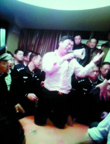 张爱华跪在桌上向群众喊话求饶